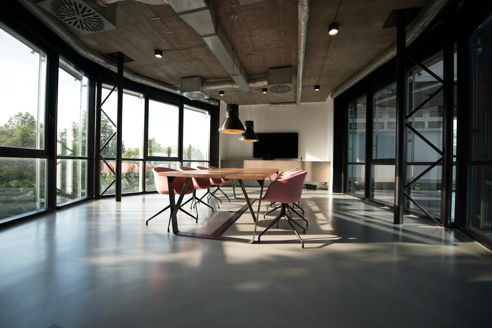 A workspace with a shared table and daylight from tall windows.