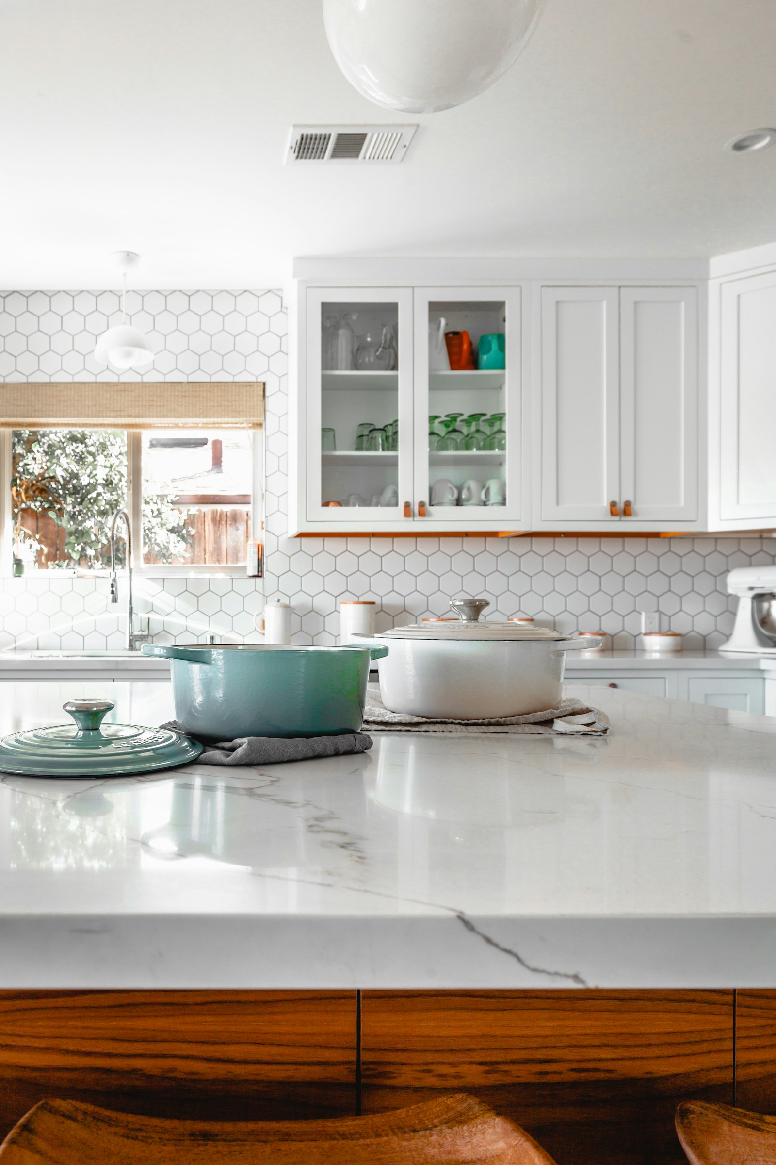 A kitchen with stone counters and pale cabinetry.